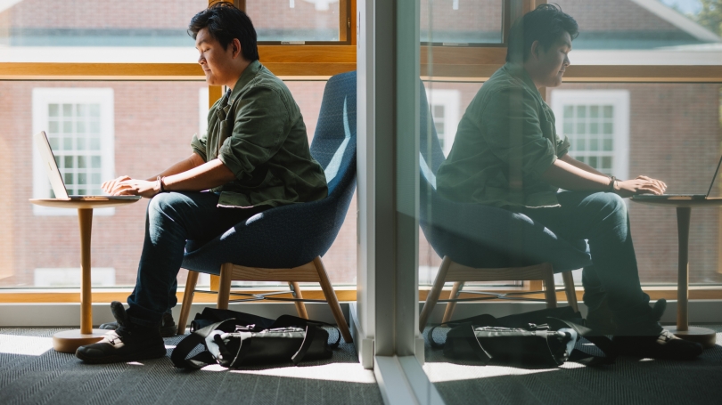 Andrew Shi '26 Sitting with Laptop in Double Reflection