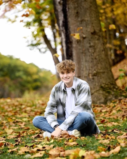 A pic of a guy smiling in the middle of foliage.
