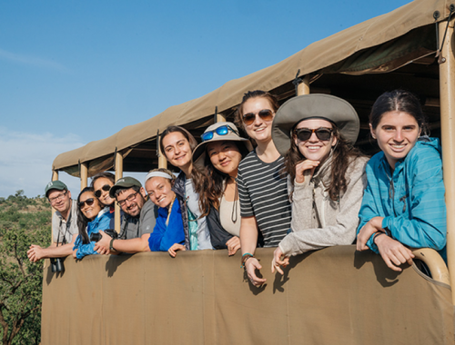 Students pose in a van on safari.