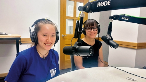 Two figures in a recording booth. 