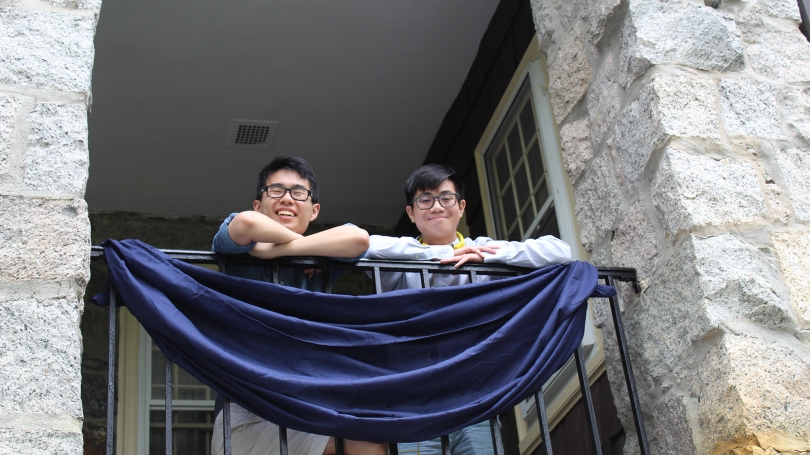 Two students smile down from the balcony.
