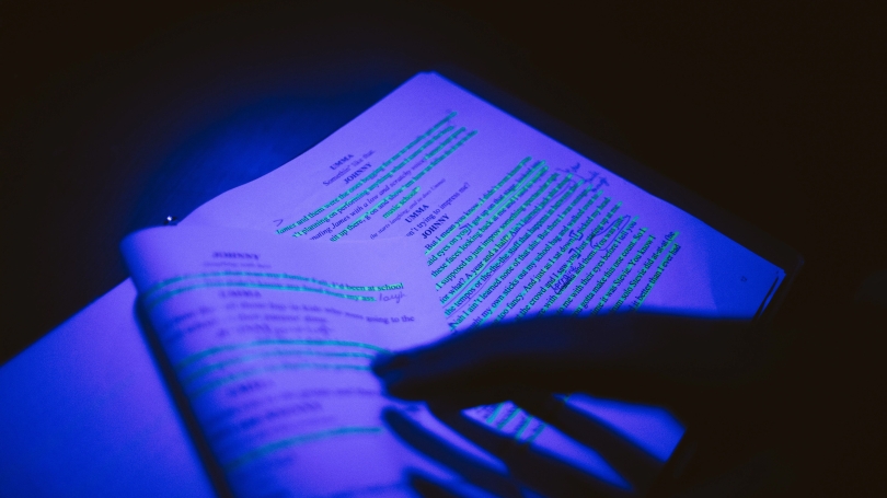 Student reading script of writing under blacklight conditions.