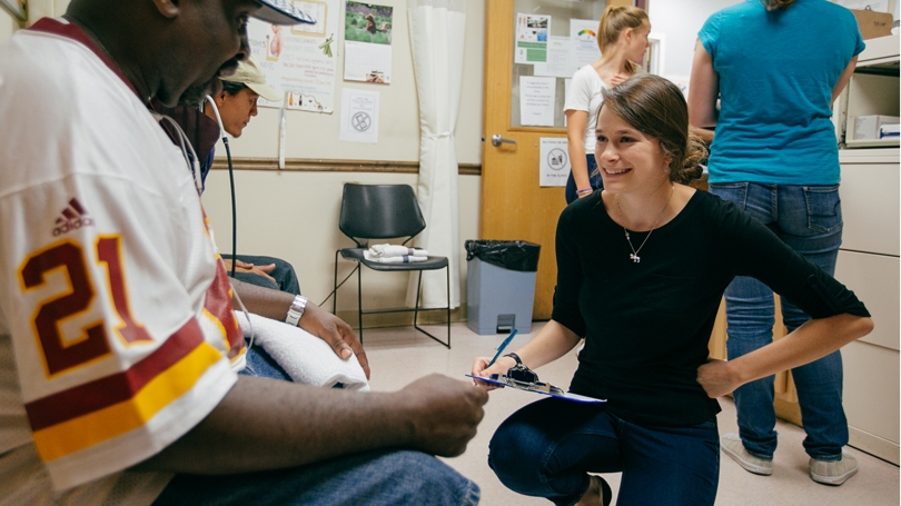 Public health intern Emma Hartswick ’17 helps a client tend to an aching foot. 