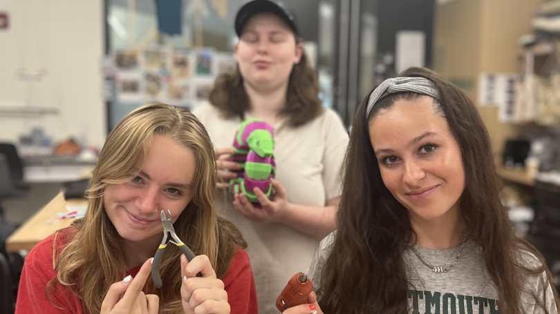 Three high school students using tools in a makerspace. 