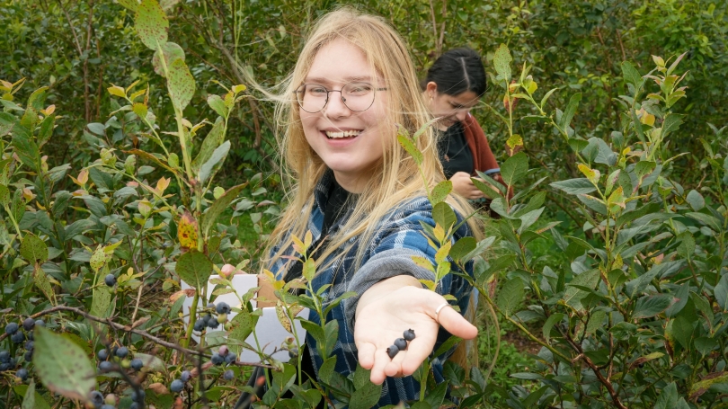 Student offering a handful of blueberries