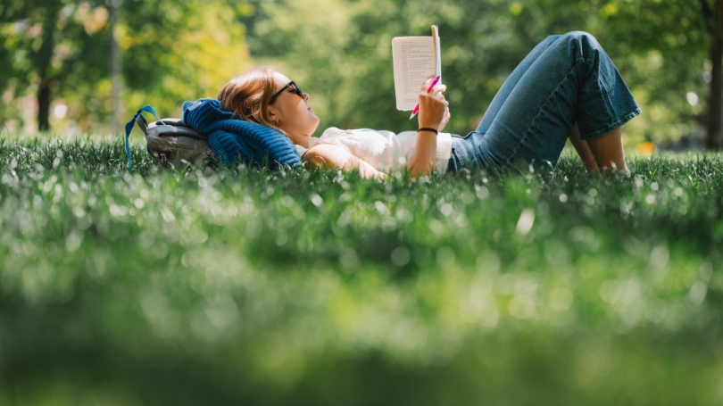 Student lying in the grass reading