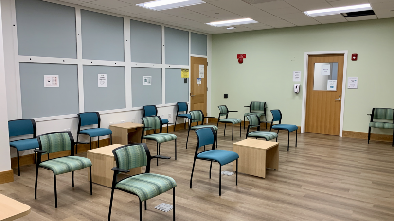 Photo of a waiting room with soft blue and green walls, abundant lighting, and well spaced vibrantly colored waiting room seats