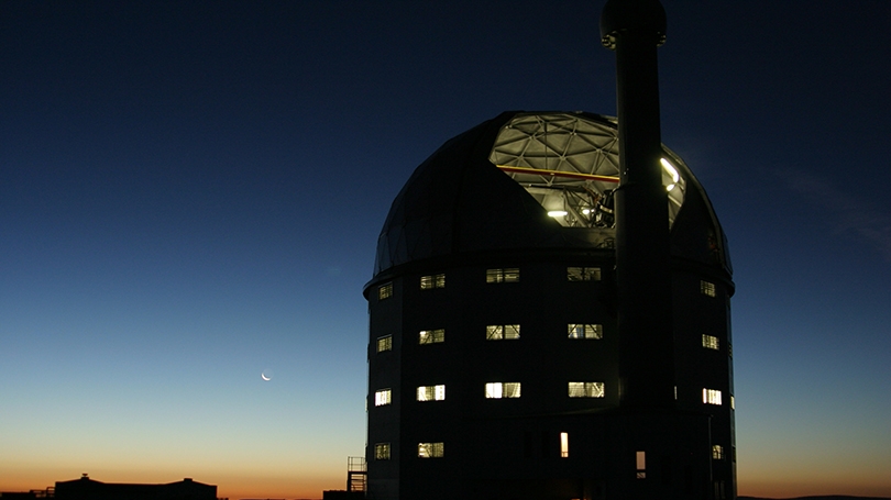 a silhouette of an observatory building against a sunset sky