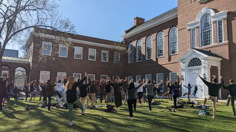 people participating in Qi Gong mindful movement on grass in front of brick building