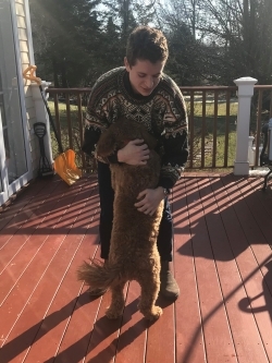 man hugging dog on porch