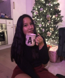 person holding mug in front of christmas tree