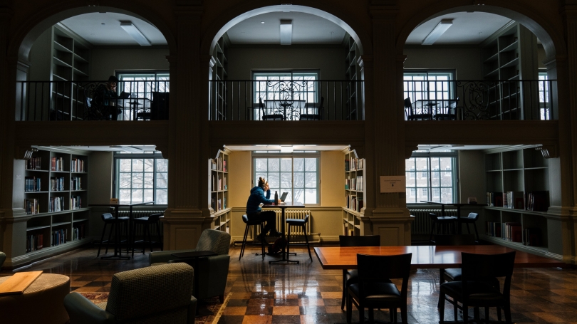 Photo of student studying alone, late in the day in a darkened East Reading Room in Baker Library
